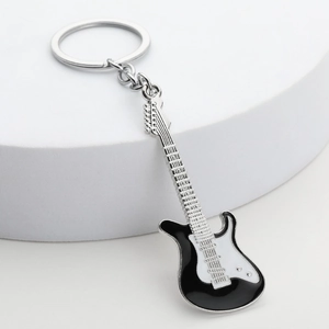 Macro detail of a black and white electric guitar keychain on a minimalist white stand