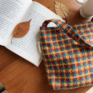Detail shot of vintage knit handbag with orange and blue plaid pattern on wooden table