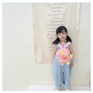 Pink toddler backpack featuring vibrant dinosaur patterns on a young model