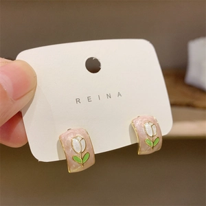 Détail de boucles d'oreilles tulipes en émail rose avec plaquage or et motifs