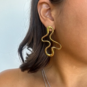 Abstract gold titanium steel earrings with irregular wavy lines on female model