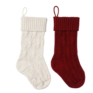 Detail of cable knit Christmas stockings in cream and dark red with hanging loops