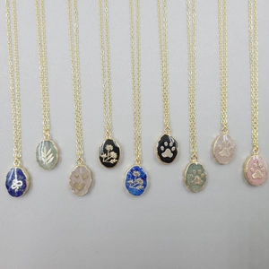 Close-up of assorted stainless steel pendants with engraved nature patterns and stones