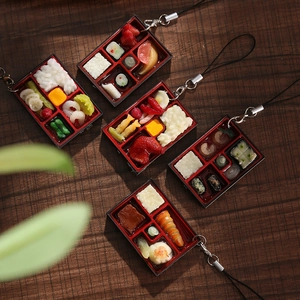 Vue macro de cinq porte-clés miniatures réalistes de boîtes bento sur un bureau