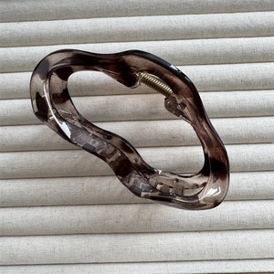 Detailed close-up of amber leopard print cloud hair claw clip on beige ribbed fabric