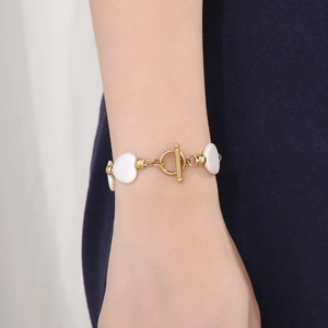 Gros plan d'un bracelet en acier doré avec breloque cœur en nacre et fermoir à bascule T