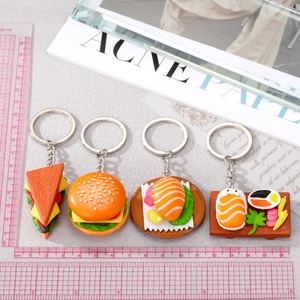 Size comparison of four miniature food keychains including sushi burger and sandwich