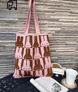 Detail of pink and brown knitted tote bag with cute rabbit pattern in casual setting