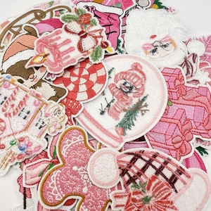 Close-up of pink Christmas embroidery patches set with Santa and gingerbread man designs