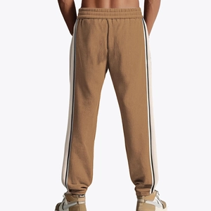Men's tan corduroy sweatpants featuring side stripes and elastic cuffs in back view