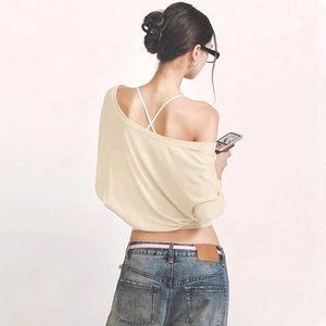 Detail of beige off-shoulder knitted top with criss-cross back straps and blue denim