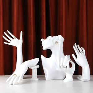 White mannequin bust and hand models for jewelry display on dark red velvet backdrop
