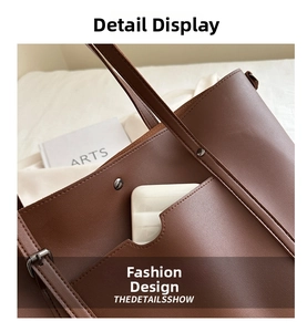 Detail of dark brown leather tote bag showing front pocket stitching and strap adjustment