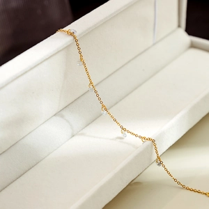 Detail of a minimalist gold chain bracelet featuring dangling round sparkling crystals
