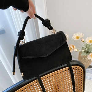 Minimalist black faux suede flap handbag with golden hardware and a woven top handle
