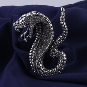 Close-up of vintage silver cobra brooch with sparkling crystals on dark silk fabric
