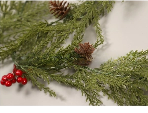 Close-up of Christmas pine garland with red berries and pine cones for festive decoration