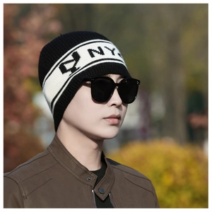 Gros plan du bonnet en maille montrant les rayures noires et blanches et le logo NY