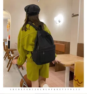 Rear view of a large black casual backpack worn by a model in a cozy cafe setting