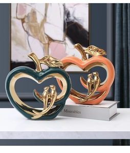 Modern ceramic apple bird sculptures with glossy glaze and gold accents on marble base