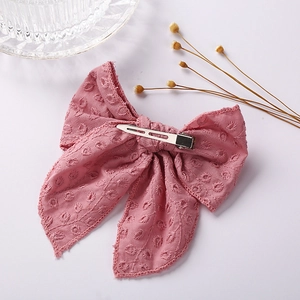 Close-up of pink embroidered fabric bow clip with silver metal alligator hair attachment