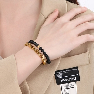 Detail of men's layered black onyx bead bracelet and gold stainless steel chain link