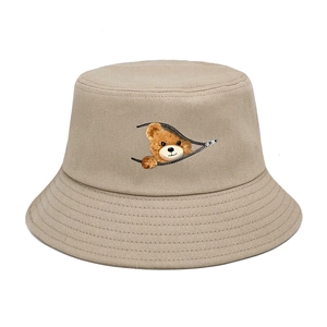 Detail of khaki cotton bucket hat featuring a creative cartoon bear peaking through zipper