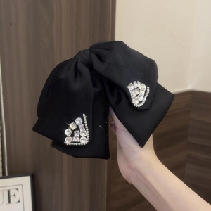 Close-up of black satin bow hair claw clip with sparkling rhinestones details