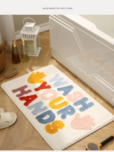 Detailed texture of colorful Wash Your Hands absorbent bathroom mat on wooden floor