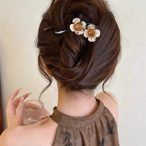 Detail of twisted hair clip with yellow flowers worn on an elegant brown updo hair style