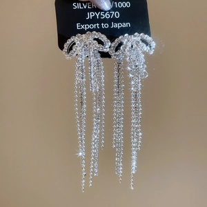 Macro shot of silver bow tassel earrings with sparkling rhinestones on 925 silver needles