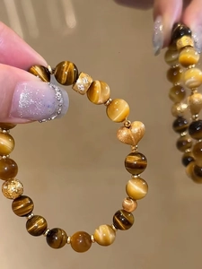Makrodetail von Tigerauge-Perlen mit goldenem Herzanhänger und Zirkonia-Abstandshalter