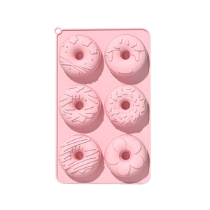 Pink 6-cavity silicone donut baking mold with various shapes on white background