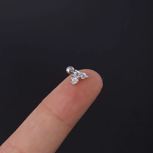 Macro view of tiny triple zircon flower stud earring held on a fingertip for size