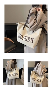Detail of canvas tote bag with brown leather straps and HONGSH printed lettering