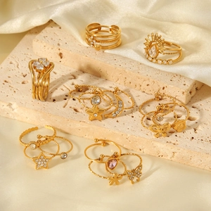 Close-up of gold stacked rings set with zircon and heart charms on stone surface