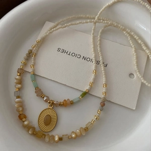 Macro shot of gold oval pendant with natural tiger eye stone and multi-layer beads