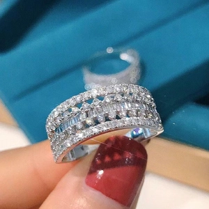 Close-up of a wide hollow multilayer ring featuring tiered baguette and round diamonds