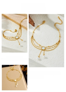 Detailed macro view of triple-layered gold anklet with shell flower and pearl accents