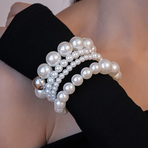 Détail d'un ensemble de bracelets en perles multicouches avec boule argentée au poignet