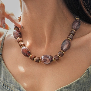 Gros plan détaillé du collier de perles bohème avec texture marbre rouge et séparateurs dorés