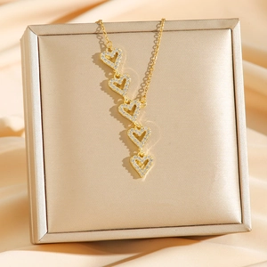 Luxe gold titanium steel necklace featuring five diamond-encrusted hearts on a box