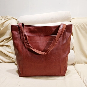 Détail du sac cabas vintage en cuir marron avec une poche frontale et bandoulière textile