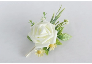 Close-up of a white rose wedding boutonniere with silk ribbon and small daisies