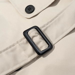 Détail d'un trench-coat beige avec texture en sergé et boutons en résine noire