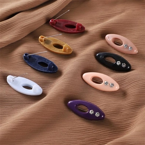 Close-up of colorful rhinestone hijab pins and plastic brooch clips on brown fabric