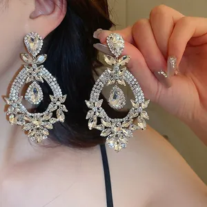 Détails de boucles d'oreilles pendantes argentées avec cristaux et design losange luxueux