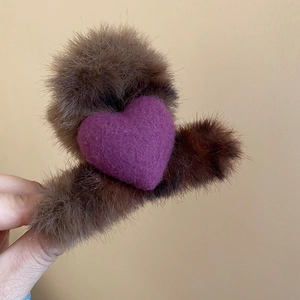 Gros plan sur une pince à cheveux pelucheuse marron avec un petit cœur rouge d'automne