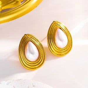 Detailed view of teardrop pearl earrings with gold layered ripple metal setting on stone