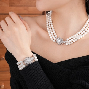 Close-up of multi-layer pearl necklace and bracelet with silver flower-shaped clasps